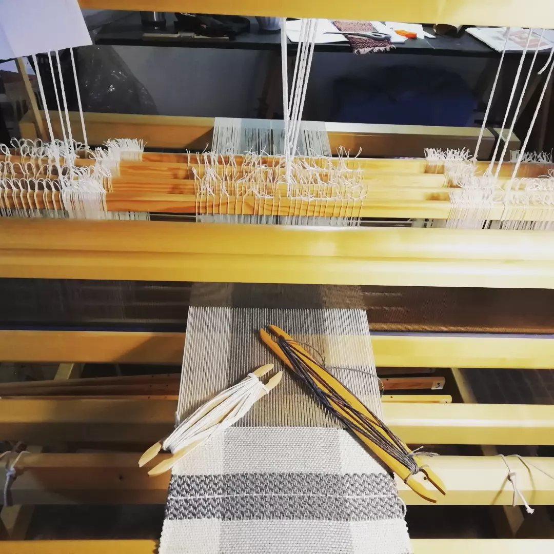 Tecido a nascer no tear, com as lançadeiras pousadas